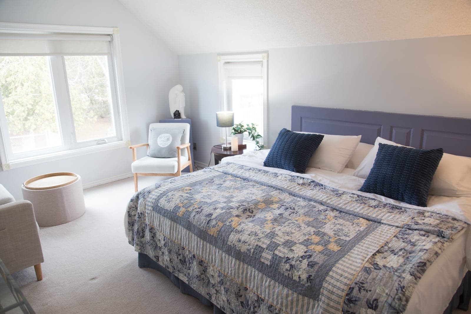 The Blue Room made up as a king bed, with navy cushions against a slate-blue headboard beneath a sloped attic ceiling