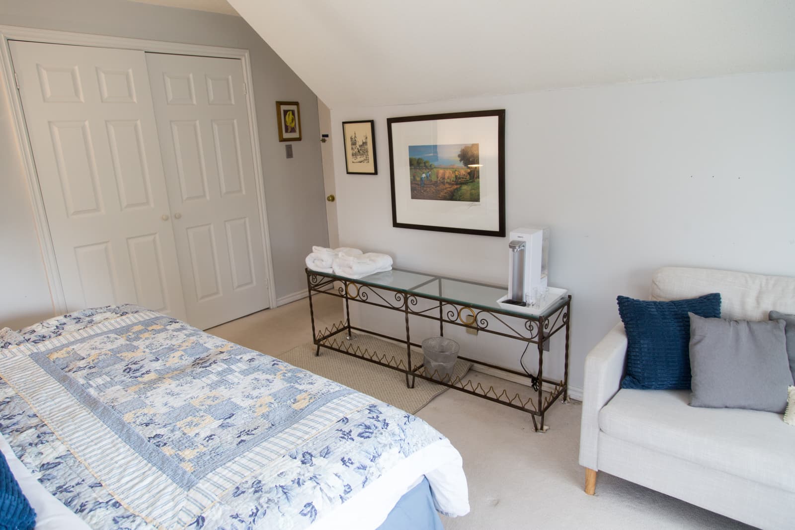 The corner of the Blue Room, with the closet, fresh towels and the Brita water machine on a glass console beneath framed artwork